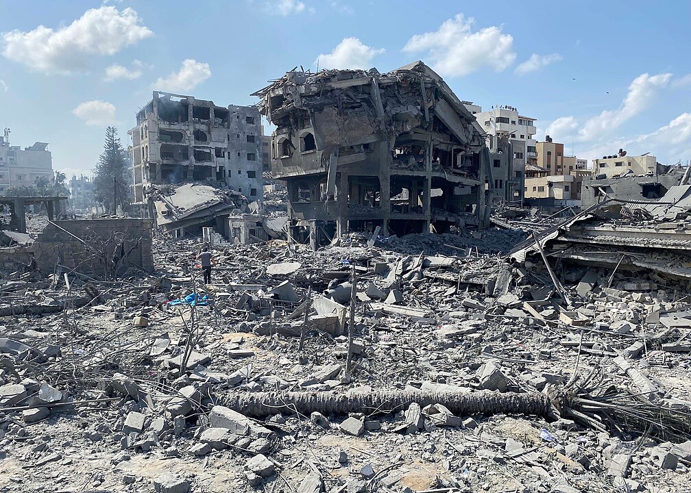 Das Foto zeigt zerbombte Häuser. Ein Mann steht im Trümmerfeld.