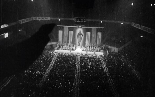 Blick auf die Bühne im Madison Square Garden. Im linken Bildbereich ist ein zum Hitler Gruß ausgestreckter Arm als Schatten zu sehen. Blick auf die Bühne im Madison Square Garden. Im linken Bildbereich ist ein zum Hitler Gruß ausgestreckter Arm als Schatten zu sehen.