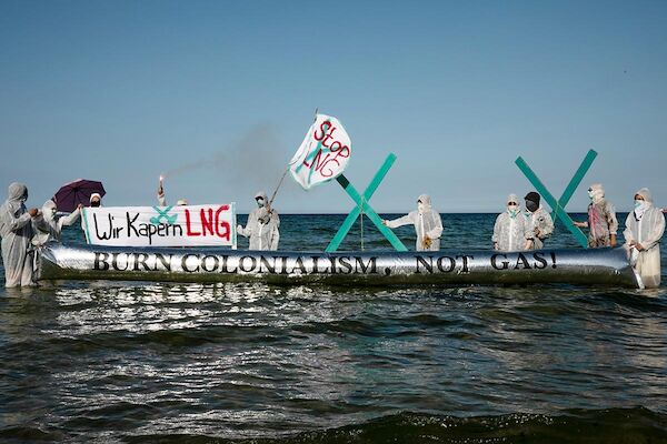Foto: © catwithanicecamera via Umbruch Bildarchiv Das Foto zeigt Aktivist:*Innen im Wasser stehend mit Bannern und einem großen Folienballon mit der Aufschrift 'LNG=NewoCo²lonialismus'