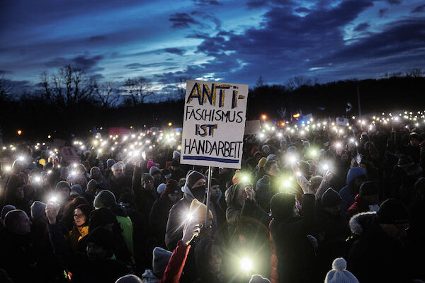 Foto: © OIiver Feldhaus via Umbruch Bildarchiv Das Foto zeigt ein Demoplakat mit dem Text "Antifaschismus ist Handarbeit" inmitten einer Menge von Menschen