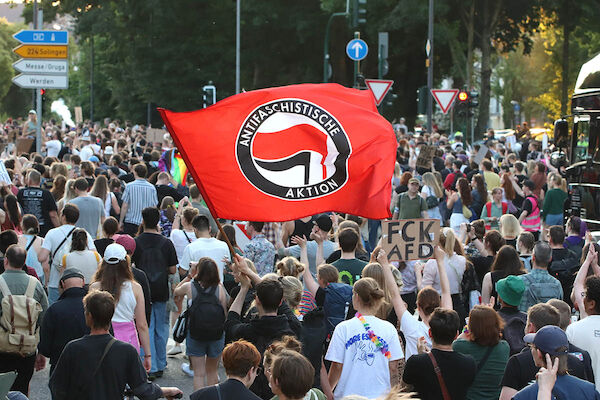 Foto: © Kinkalitzken via Umbruch Bildarchiv Das Fotos zeigt die vom betrachter wegziehende Demo mit einer großen Antifaschistische Aktion Fahne" und einer Texttafel mit dem Text: "FCK AfD" (Fick AfD)