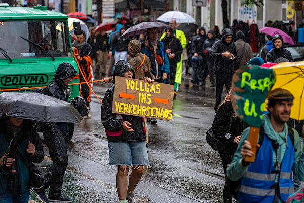 Das Foto zeigt einen Teilnehmer der Demo mit einem Pappschild auf dem "Mit Vollgas ins Verkehrschaos" steht.