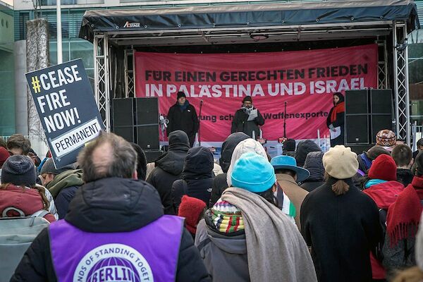 Das Foto zeigt die Rednerbühne mit dem Transparenttext "Für einen gerechten Frieden in Palästina und Israel"