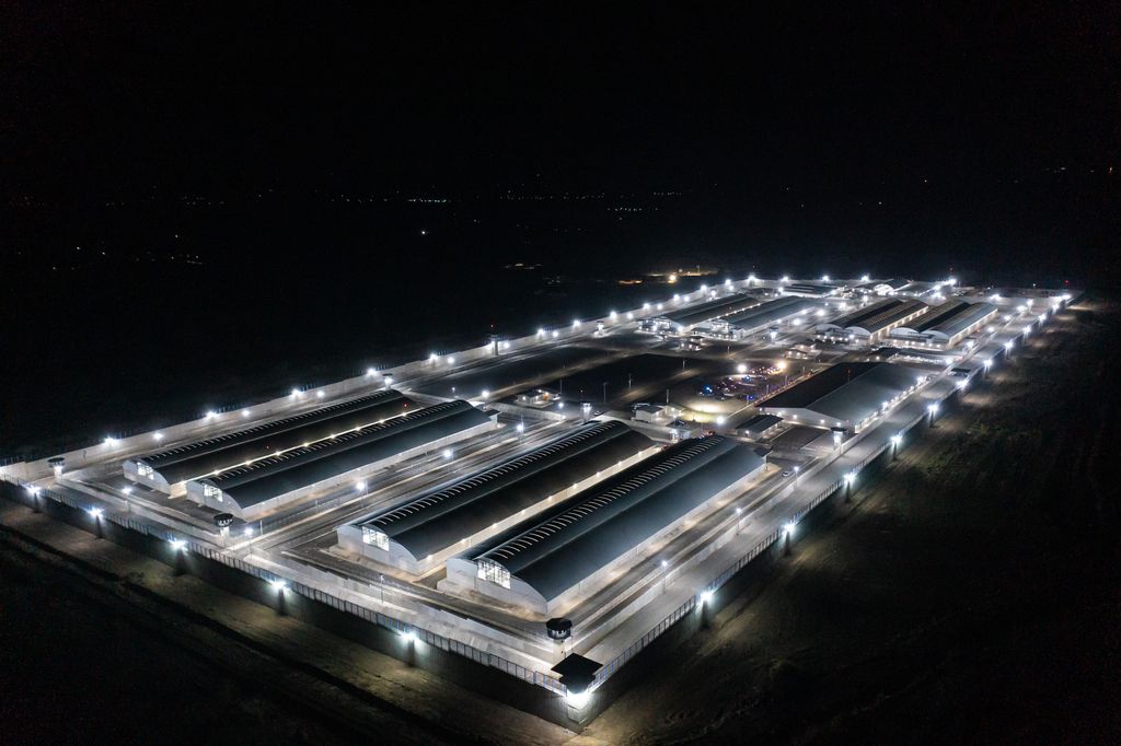 Das Luftbild zeigt das hell beleuchtete Hochsicherheitsgefängnis in San Vicente, El Salvador bei Nacht.