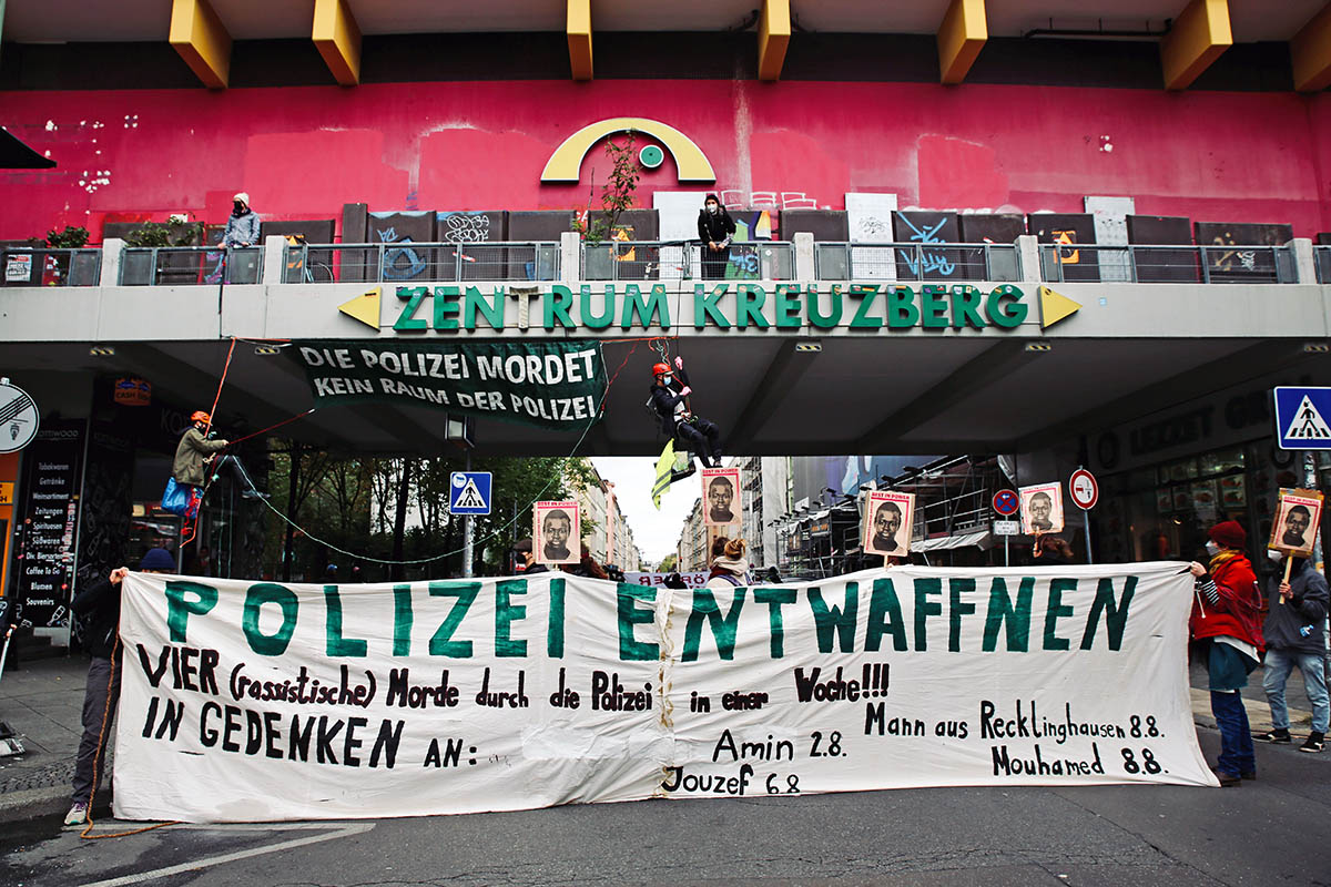Demonstrant:*innen tragen ein Transparent mit der Aufschrift "Polizei entwaffnen! Vier rassistische Morde durch die Polizei in einer Woche! In Gedenken an Amin 2.8., Jouzef 6.8., Mann aus Recklinghausen 8.8., Mouhamed 8.8." Demonstrant:*innen tragen ein Transparent mit der Aufschrift "Polizei entwaffnen! Vier rassistische Morde durch die Polizei in einer Woche! In Gedenken an Amin 2.8., Jouzef 6.8., Mann aus Recklinghausen 8.8., Mouhamed 8.8."