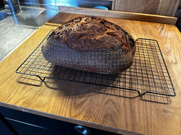 Ein rustikal aufgerissener Brotlaib liegt auf einem Auskühlgitter. Ein rustikal aufgerissener Brotlaib liegt auf einem Auskühlgitter.