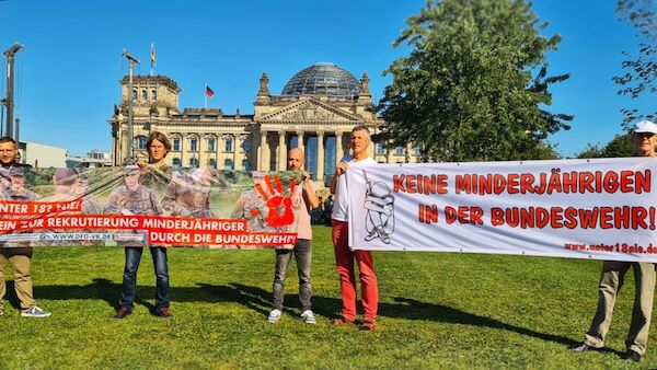 Foto: Bündnis "unter 18 nie!" vor dem Reichstag mit 2 Transparenten gegen die Rekrutierung Minderjährger